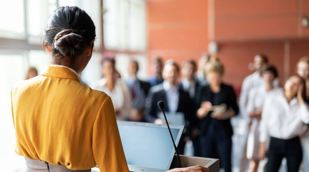 Woman speaking in a room full of people